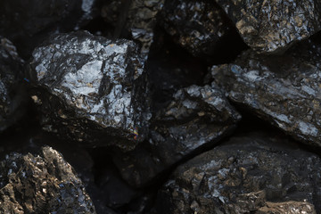Black coal mine close-up with soft focus. Anthracite coal bar on dark background. Natural black coal bars for background. Industrial coal nuggets close up