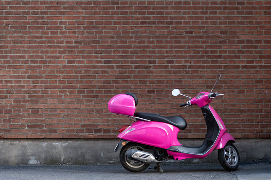 Pink Scooter in front of a brick wall