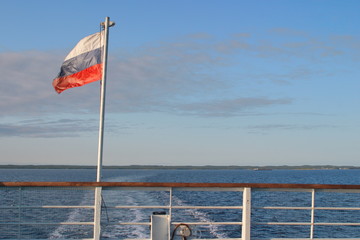 Fototapeta premium The image of the flag on the stern of the ship and the Wake