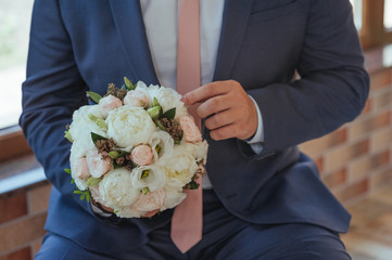 Groom hand holding bouquet fresh flowers close up in pink and white colors