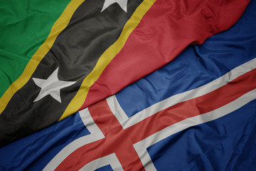 waving colorful flag of iceland and national flag of saint kitts and nevis.