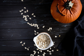 Halloween pumpkin and seeds on dark wooden background