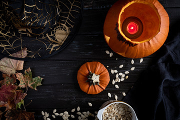 Halloween pumpkin and seeds, witch hat on dark wooden background