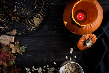 Halloween pumpkin and seeds, witch hat on dark wooden background