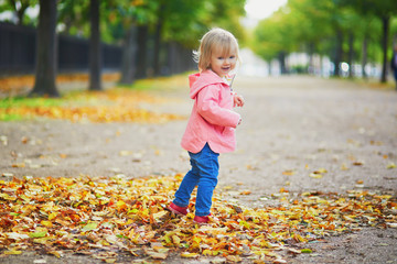 Adorable cheerful toddler girl running in park in Paris, France