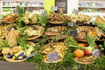 Mushrooms and vegetables on stand in supermarket in France. 