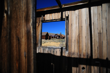 Vilalggio desertico visto attraverso finestra di capanna in legno abbandonata