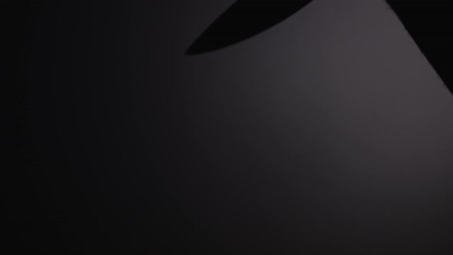 Shadow of killer holding knife cast on wall. Raising knife and stabbing. Silhouette of arm and hand holding blade.