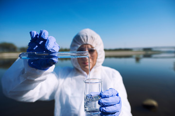 Close up view of ecologist sampling water from the river with test tube. Examining level of...
