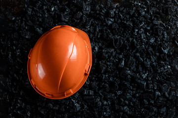 An orange helmet of a miner lies on a heap of coal, open pit coal mining, copy space. Fossil fuels,...