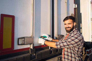 Truck driver opening back of the truck trailer ready to unload goods. Transportation services.