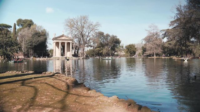 Spring time in Italy, natural Roman park in a sunny day. Beautiful lake in Villa Borghese, ducks swimming and people riding on catamaran. Place of peace, tranquility and relaxation. Spring in the park