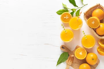 Fototapeten Orangensaft. Frisch gepresster Saft in Gläsern und frische Früchte mit Blättern, Ansicht von oben © Sea Wave