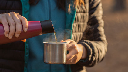Fototapeta na wymiar Woman pouring hot drink from thermos into mug