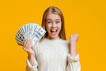 Ecstatic teen girl rejoicing success and holding lots of cash
