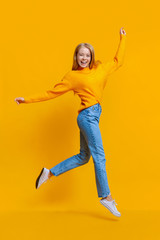 Fototapeta na wymiar Portrait of cute teen girl jumping on orange background