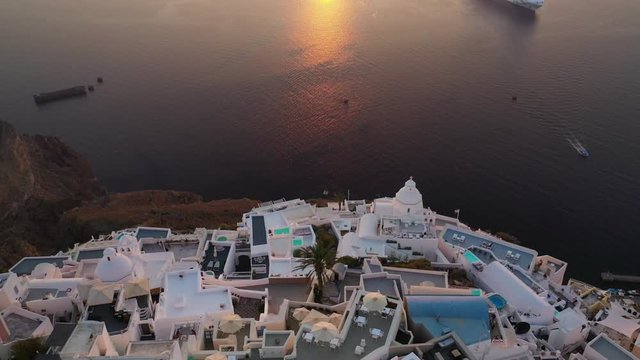 Aerial drone video of beautiful picturesque village of Fira built on top of a cliff with breathtaking view at sunset, Santorini volcanic island, Cyclades, Greece