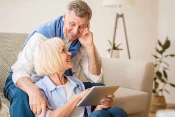 Happy elderly couple searching film on digital tablet