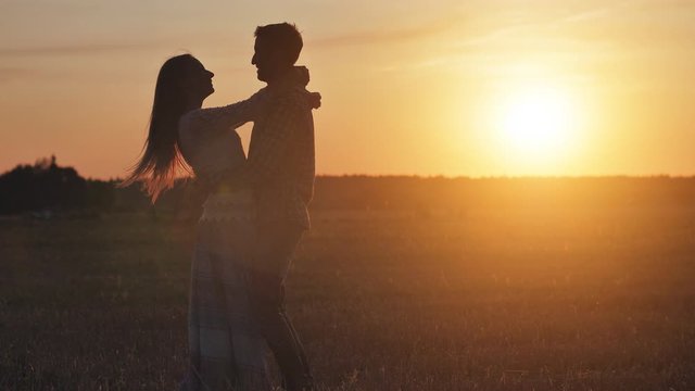 Silhouette of a loving couple hugging on a sunset background.