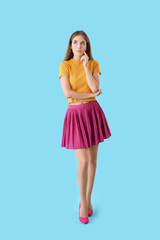 Thoughtful young woman on color background