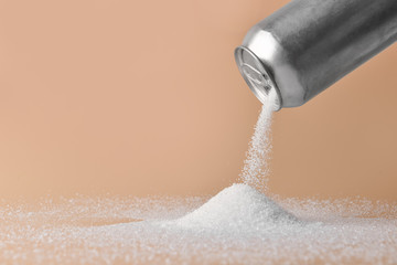Sprinkling of sugar from tin can onto color background