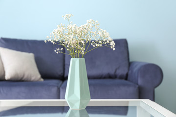 Vase with beautiful flowers on table in room