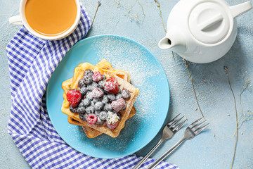 Plate with sweet tasty waffles and tea on table