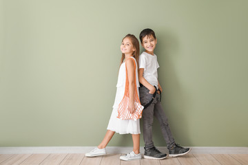 Cute fashionable children near color wall