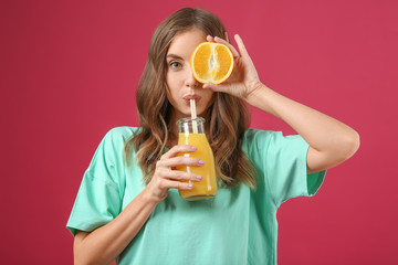 Beautiful young woman with orange juice on color background