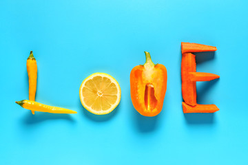 Word LOVE made of fresh vegetables and lemon on color background