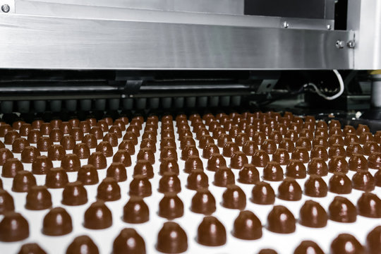 chocolate toppings on the conveyor of a confectionery factory close-up