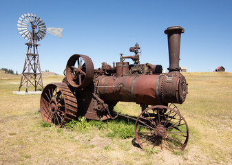 Fototapeta na wymiar old steam powered tractor rusting way in field