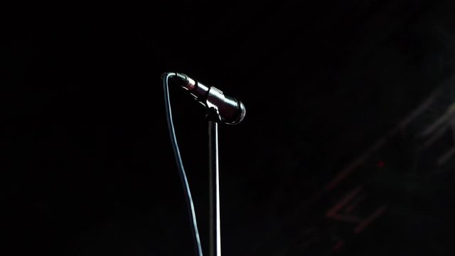 Silver microphone with a cord on a stage stand. smoke on the background from smoke machine.