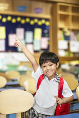 An Asian young boy with school uniform getting excited and cheerful in a classroom.