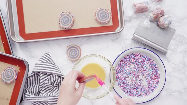 Step by step. Flat lay. Rolling edges of red, white, and blue pinwheel sugar cookies in sprinkles.