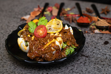 Spicy chicken curry with boiled egg garnished with lemon, tomato and coriander lief. Extra copy space for text.