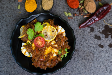 Spicy chicken curry with boiled egg garnished with lemon, tomato and coriander lief. Extra copy space for text.