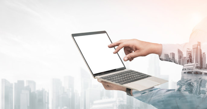 Double exposure image of businessman using computer on abstract modern city background. Future business and communication technology concept. Surreal futuristic multiple exposure graphic interface.