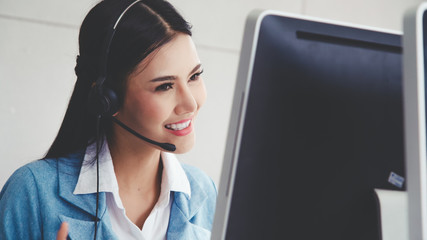 Customer support agent or call center with headset works on desktop computer while supporting the customer on phone call. Operator service business representative concept.