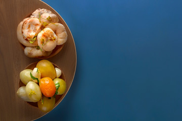 Fermented products salted tomatoes and mushrooms in a wooden bowl on a blue background. Top view. Copy space