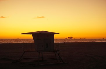 Lifeguard tower on beach with dramatic sunset