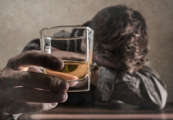 alcoholic depressed and drunk addict man sitting in front of whiskey glass trying holding on drinking in dramatic expression suffering alcoholism and alcohol addiction