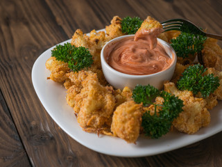 Baked cauliflower inflorescence on a fork over the sauce.