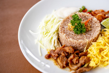 The fried rice with decorsted with dried shrimps , mango and omelette and seasoned by lime in white dish. 