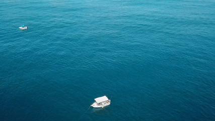 Stunning Turquoise Blue Crystal Clear Water On A Sunny Day With Small White Fishing Boat Below