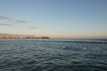 View From A Fishing Boat With Blue Water At Sunrise Towards Gold Coast City And Burleigh Headland With Orange Sky