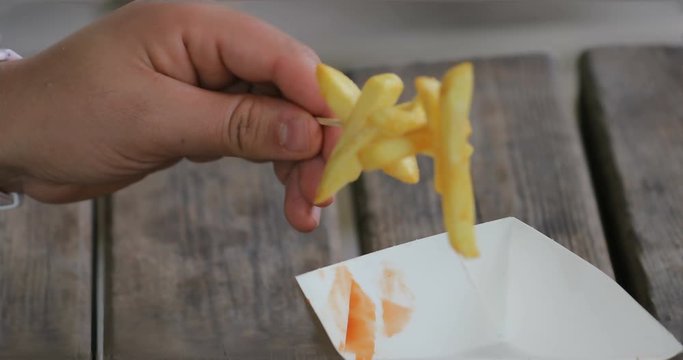 French fries strung on the stick taken with a female hand