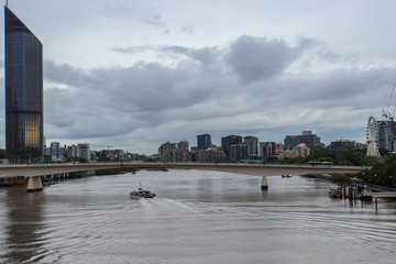 Brisbane City Skyline With High Rises Bridge And Ferry Moving Down The River On An Overcast Day