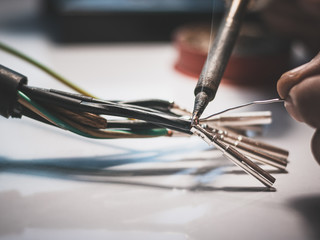 Electricians are using a soldering iron to connect the wires to the metal pin with soldering lead.
