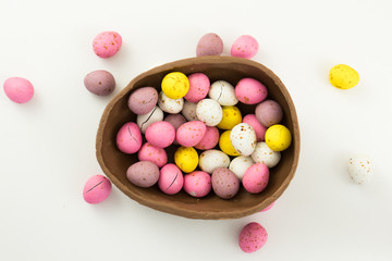 Large Chocolate Easter Egg Half Filled With Colorful Smaller Eggs On A White Studio Background